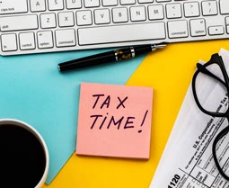 sticky note saying tax time with office items