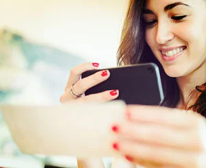 smiling person taking picture of check with smartphone