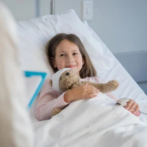 child in hospital with teddy bear